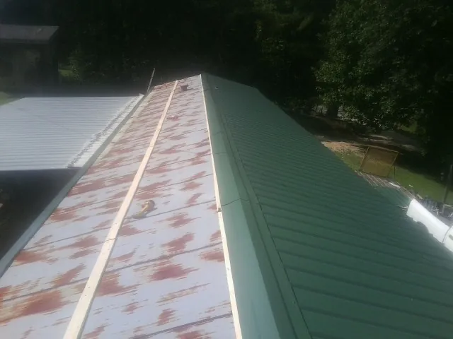 Old rusted panels beside newly installed green metal roofing — Wind Damage Roof Repair by Roofing Brothers in Earlysville