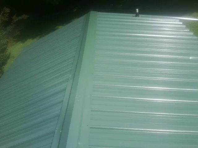 New green metal panels meeting at the ridge of a roof — Flat Roof Repair work by our crew in Earlysville