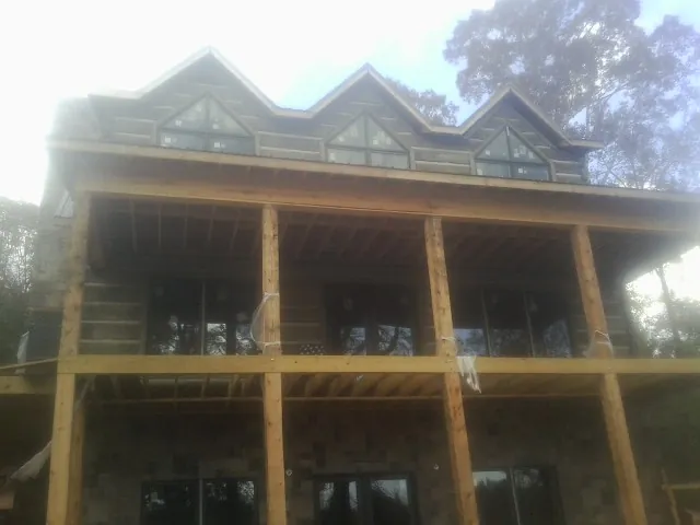 Dormers and porch framing on a large log home under construction — Roof Coating work by our crew in Earlysville