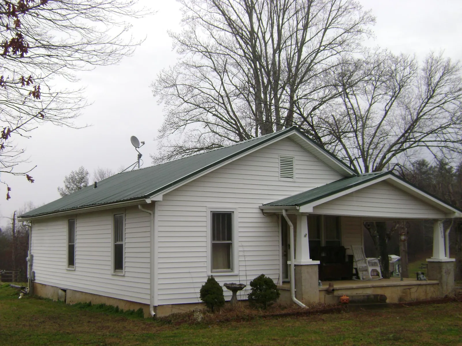 Green metal roof on a white bungalow with a side porch in Earlysville