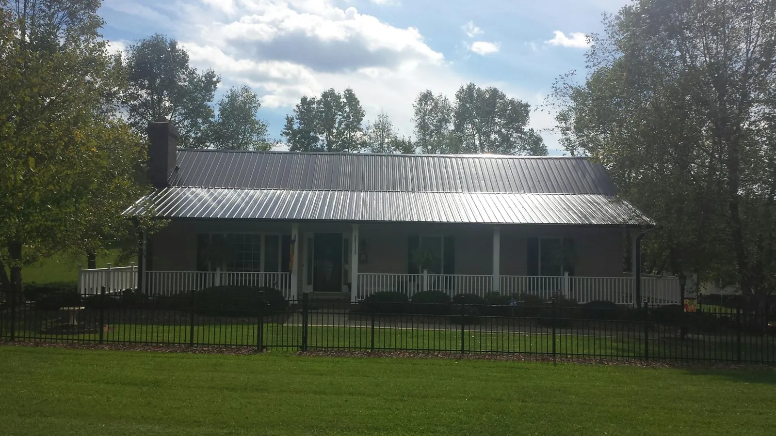 Gray metal roof on a brick ranch with a full width front porch — Gutter Guard Installation work by our crew in Earlysville