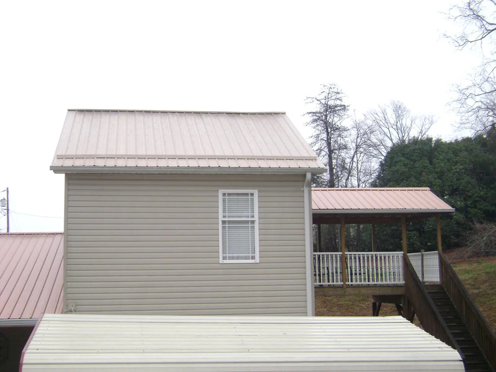 Tan metal roofs on a two story addition and attached porch, from a Roof Replacement job in Earlysville
