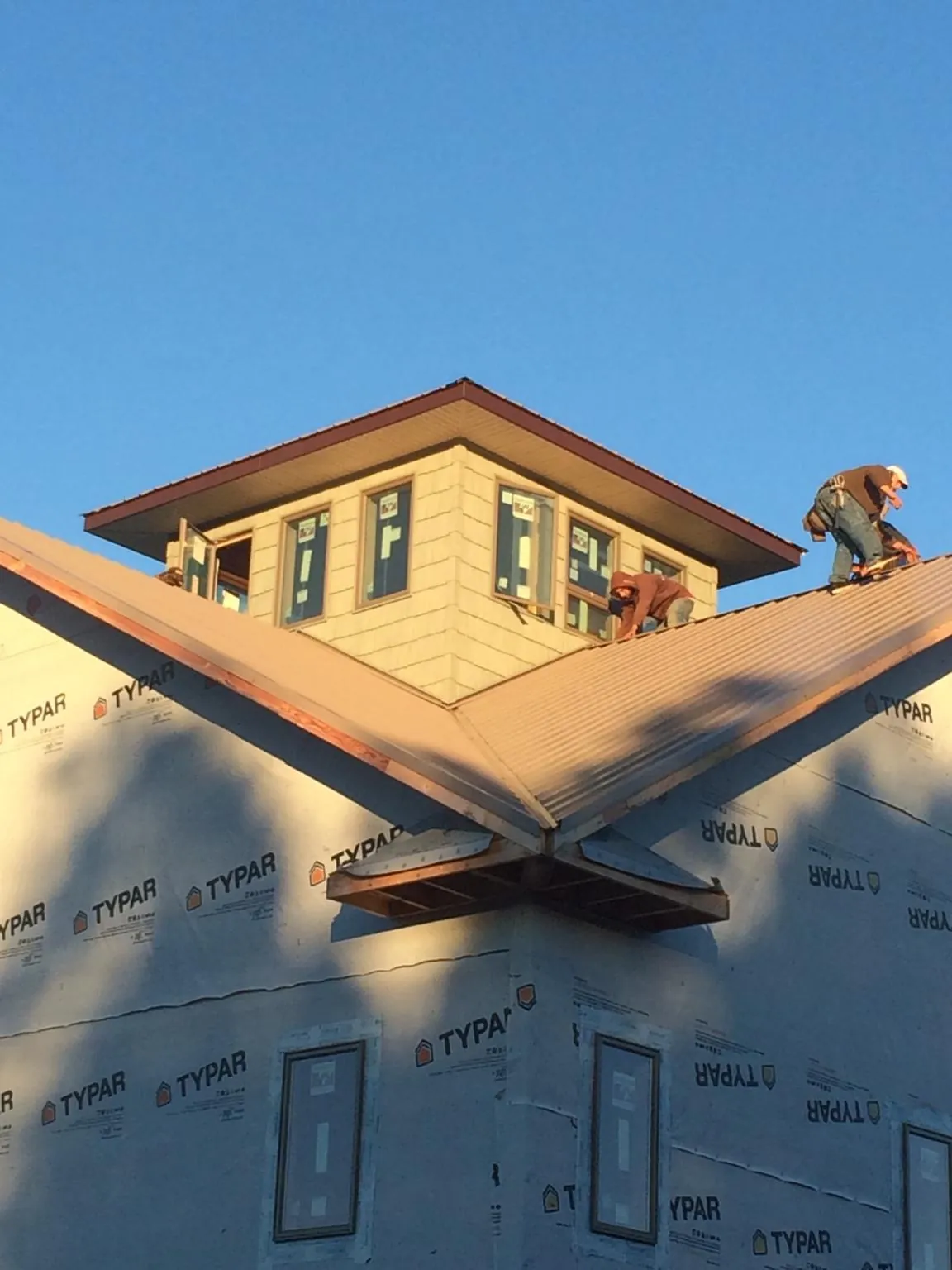 Roofers working around a rooftop cupola on a new metal roof at sunset — Roof Waterproofing in Earlysville by Roofing Brothers
